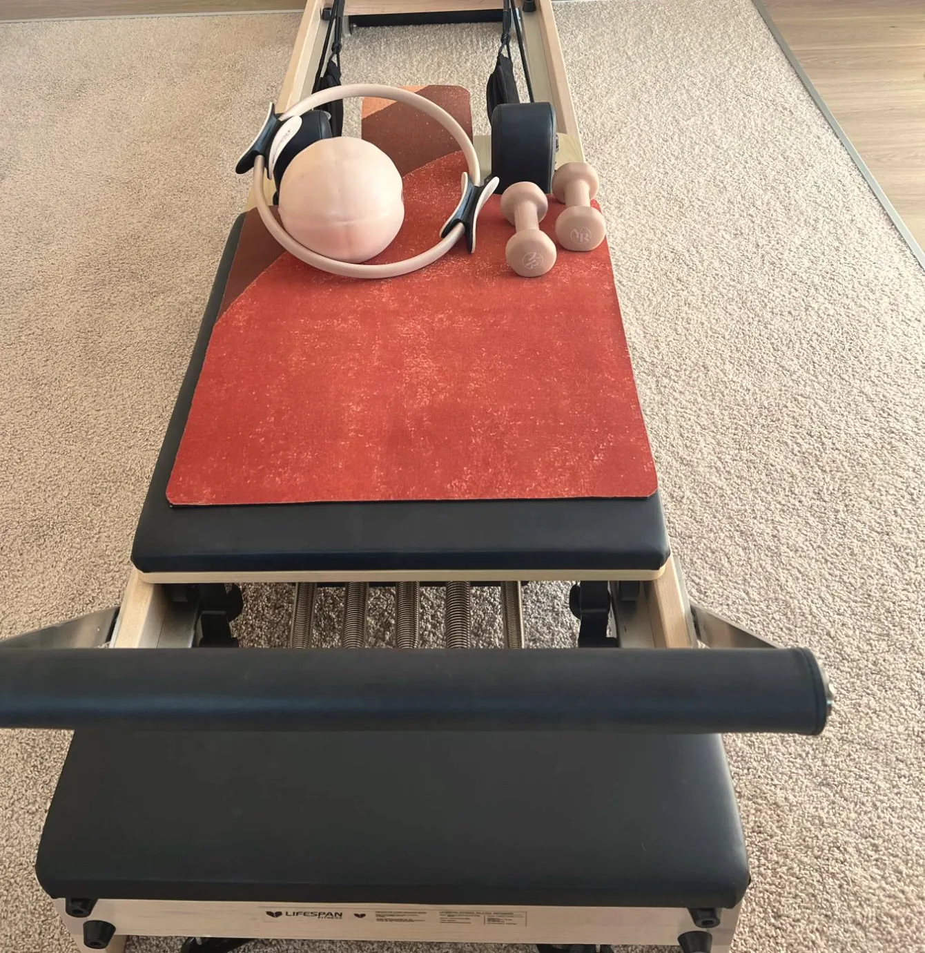 Reformer set up with a Pilates ring, ball and hand weights
